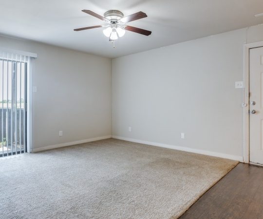 an empty room with a ceiling fan and sliding glass door at The Falltree Apartments