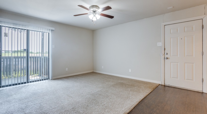 an empty room with a ceiling fan and sliding glass door at The Falltree Apartments